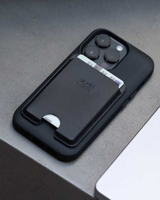 Close-up of a smartphone with a black Quad Lock MAG™ wallet accessory attached on the back, holding cards.
