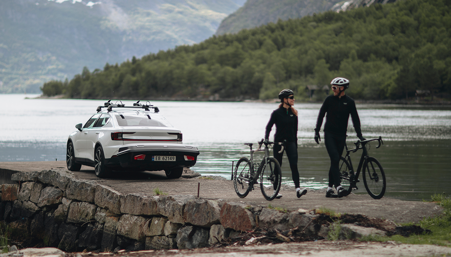Two cyclists walking with their bikes on the stone pier, next to a parked car with Thule Arcos.