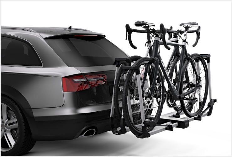 A car with a Thule hitch bike rack installed and two bikes loaded.