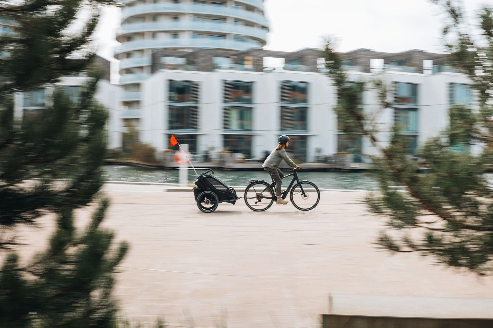 Person, die neben einem Fahrrad mit Fahrradanhänger steht und mit einem Kind interagiert.