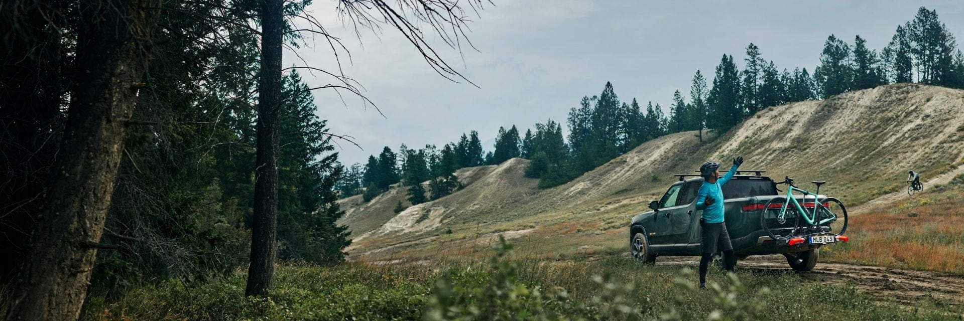 Un homme portant un casque de vélo se tient près d’un camionnette avec un vélo monté sur un porte-vélos Thule Epos. 