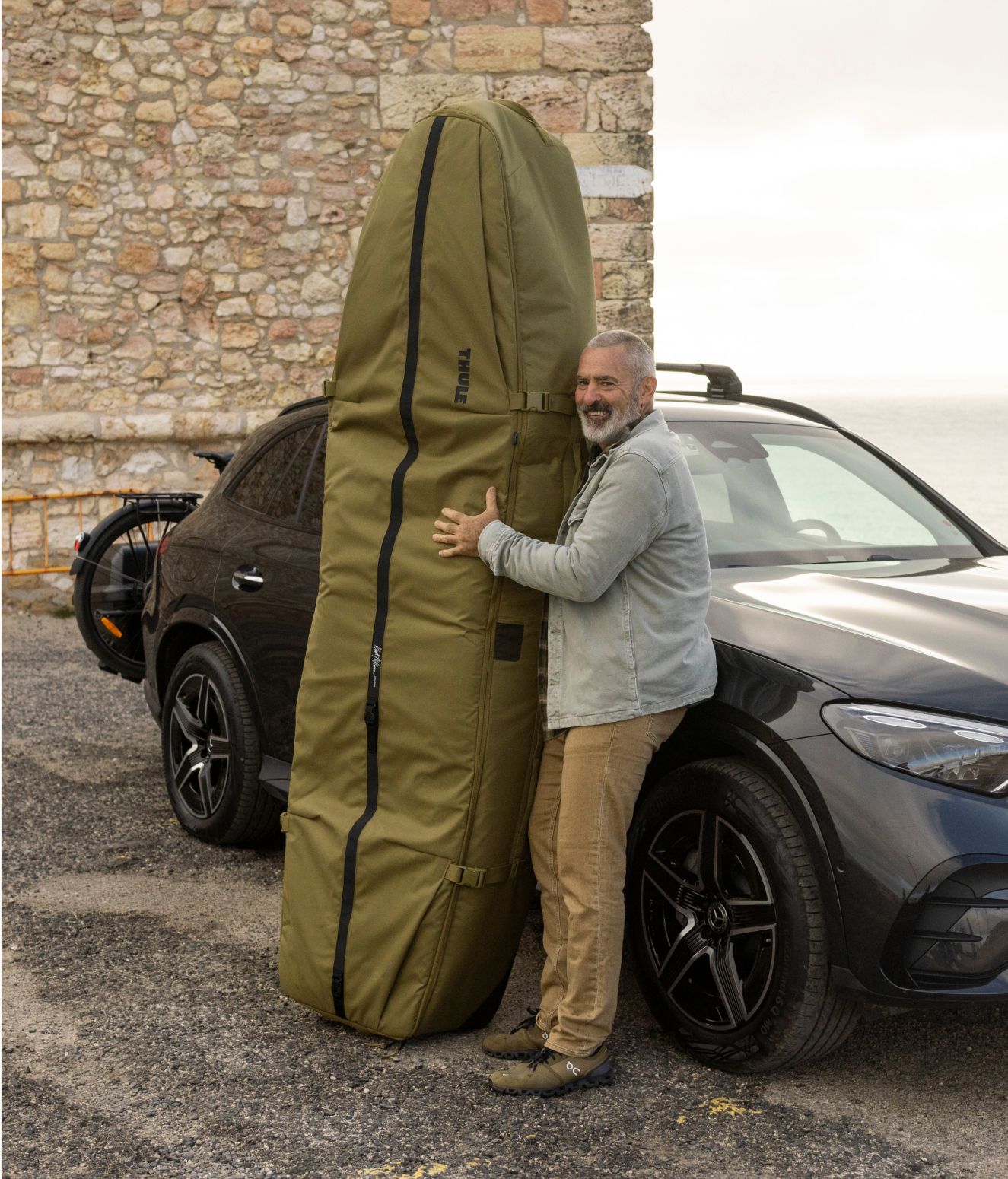 Le légendaire surfeur de grosses vagues Garret McNamara devant une voiture équipée d’un sac de surf Thule Aion qu’il a conçu en collaboration avec Thule.