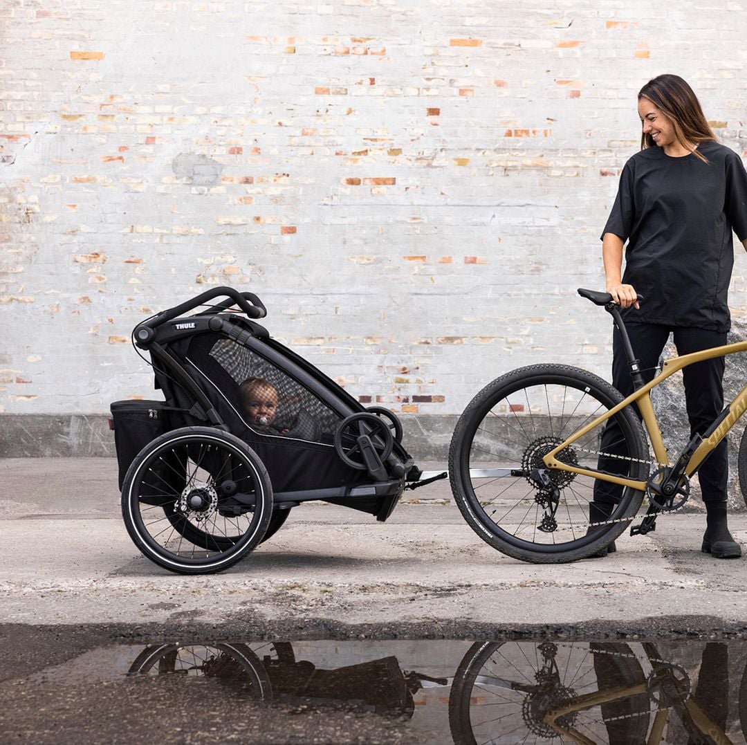 Longtail bike with two children in rear seats and a bike trailer attached.