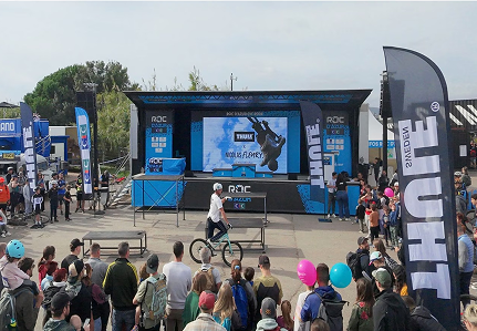 Une foule entoure un homme à vélo prêt à faire des figures. 