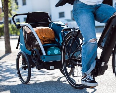 Una persona en bicicleta con mercancías dentro de un remolque de bicicleta.