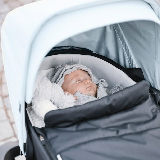 A close-up of a newborn in the Thule Shine newborn stroller bassinet.