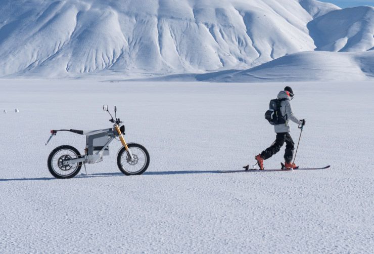 Lorenzo Alesi skiing in front of his electric motorbike with a Thule ski backpack.