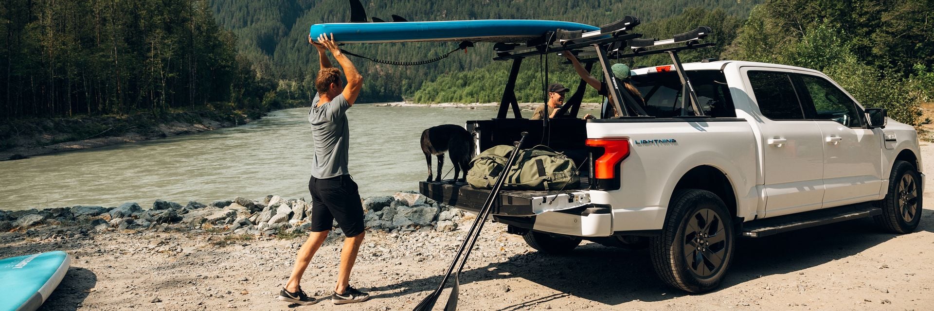 Person loading gear onto a pickup truck with a Thule Xscape truck rack.