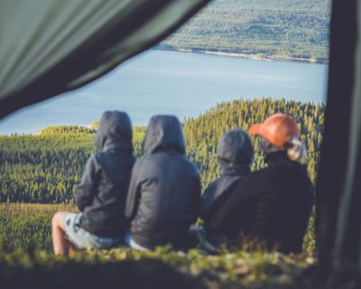 帶著孩子一起露營的一家人坐在帳篷外，眺望著遠方