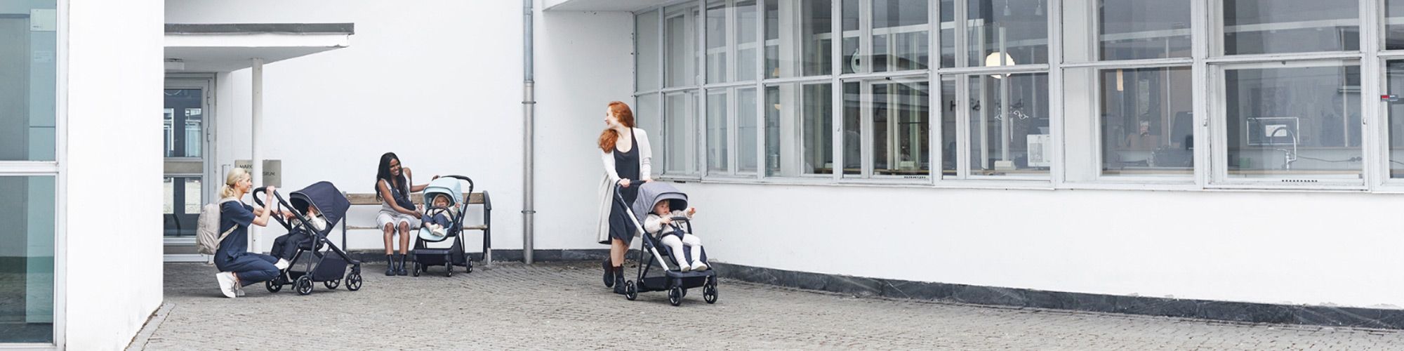 Three mothers sit outside a building with their babies in Thule Shine strollers.