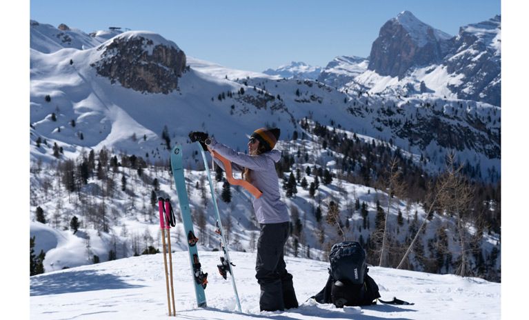 Alice Linari taking her skins off her skis on a snowy mountain with a Thule ski backpack.