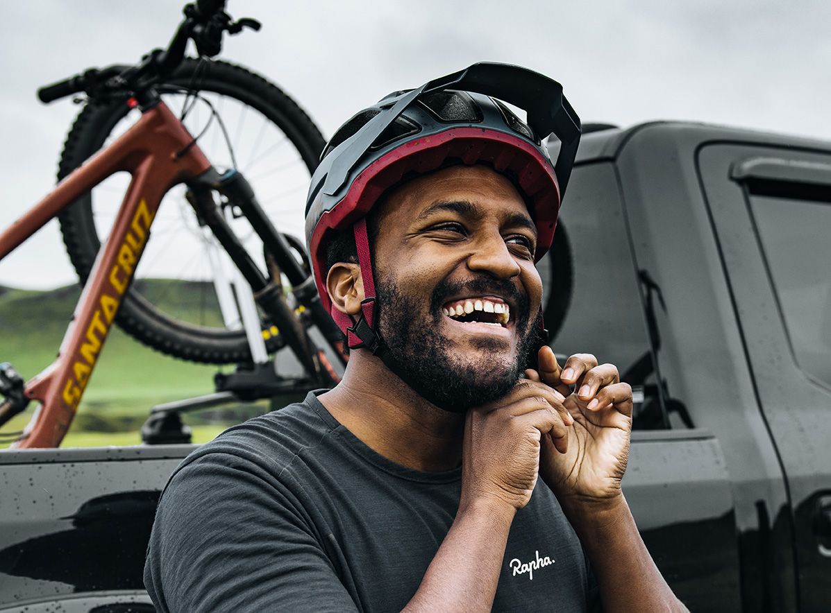 Downhill-Mountainbiker Eliot Jackson lacht, während er seinen Helm aufsetzt.