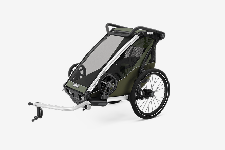 Зелёный велосипедный прицеп Thule Chariot Lite стоит на светло-сером фоне. 