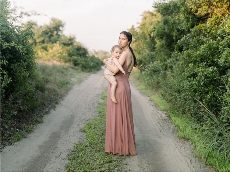 Olesia and her baby standing on the sandy road leading to Breezy Point beach.