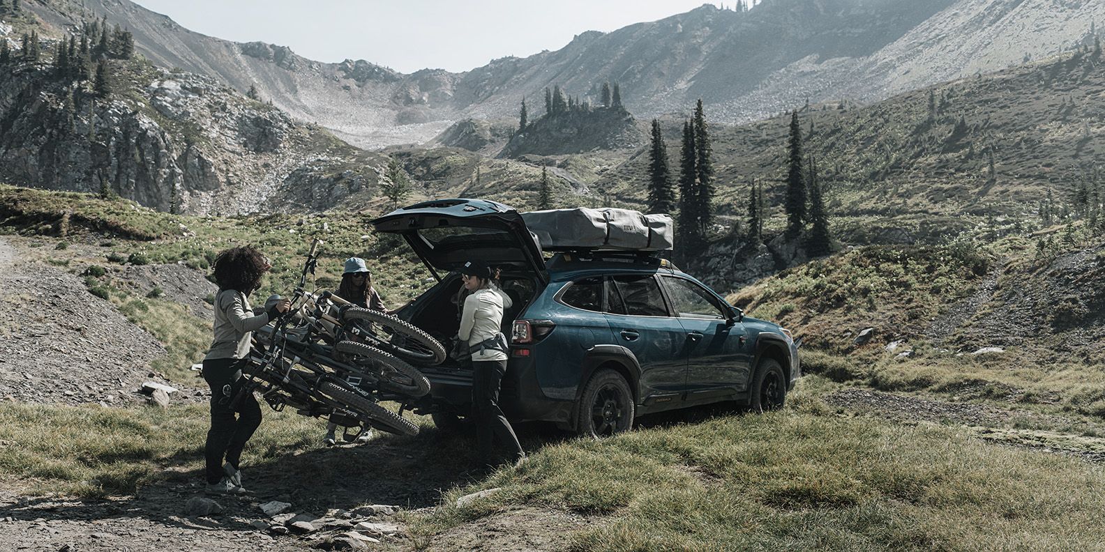 Una donna sposta il portabici Thule Epos caricato con tre bici dall'auto per accedere al bagagliaio