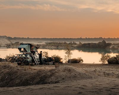 Thule rooftop tent set up by the water at sunset