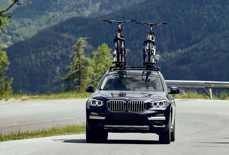 A car drives down a mountain road with a Thule bicycle rack.