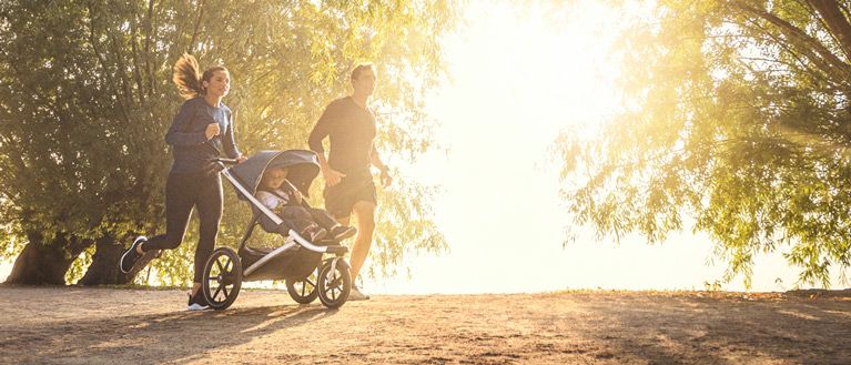 Running couple in sunrise with stroller Thule Urban Glide 2 blue