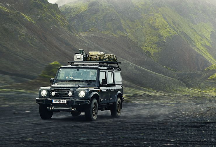 A Grenadier is driving through the Icelandic countryside with a Thule CapRock roof rack platform and gear attached.