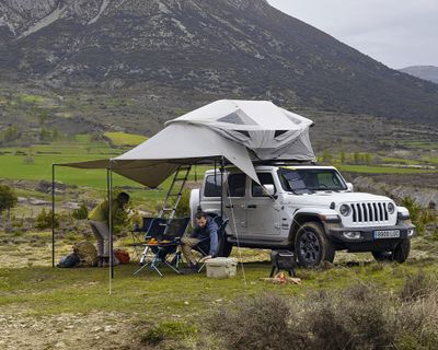 一辆吉普车停在乡间，车顶安装有 Thule Approach 车顶帐篷。