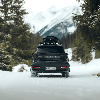 SUV s střešním boxem Thule nahoře a zadním zavazadlovým boxem Thule vzadu vysušuje zasněženou silnici.