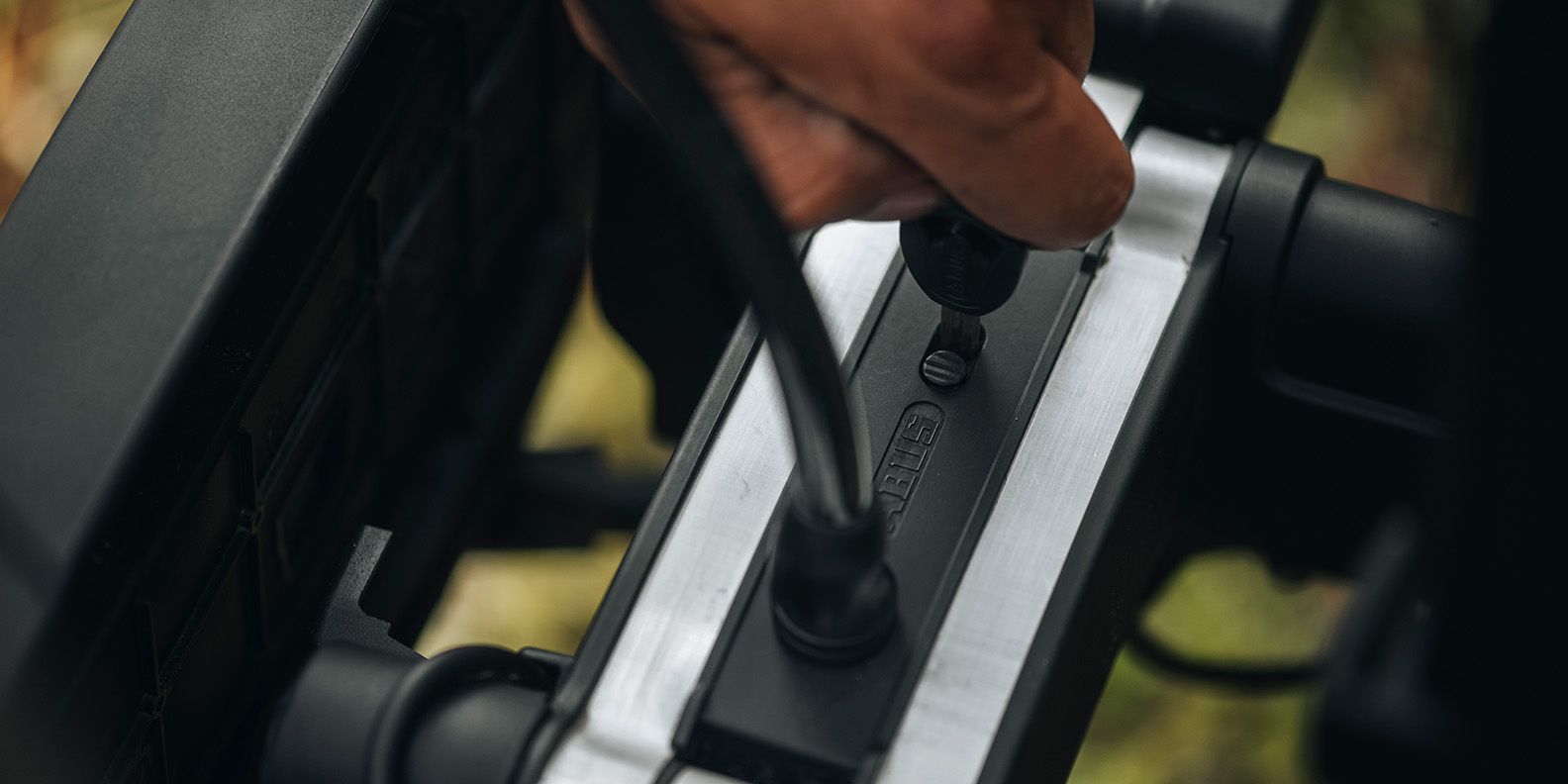 A close up of a hand locking the Thule High Grade Bike Lock (sold separately)