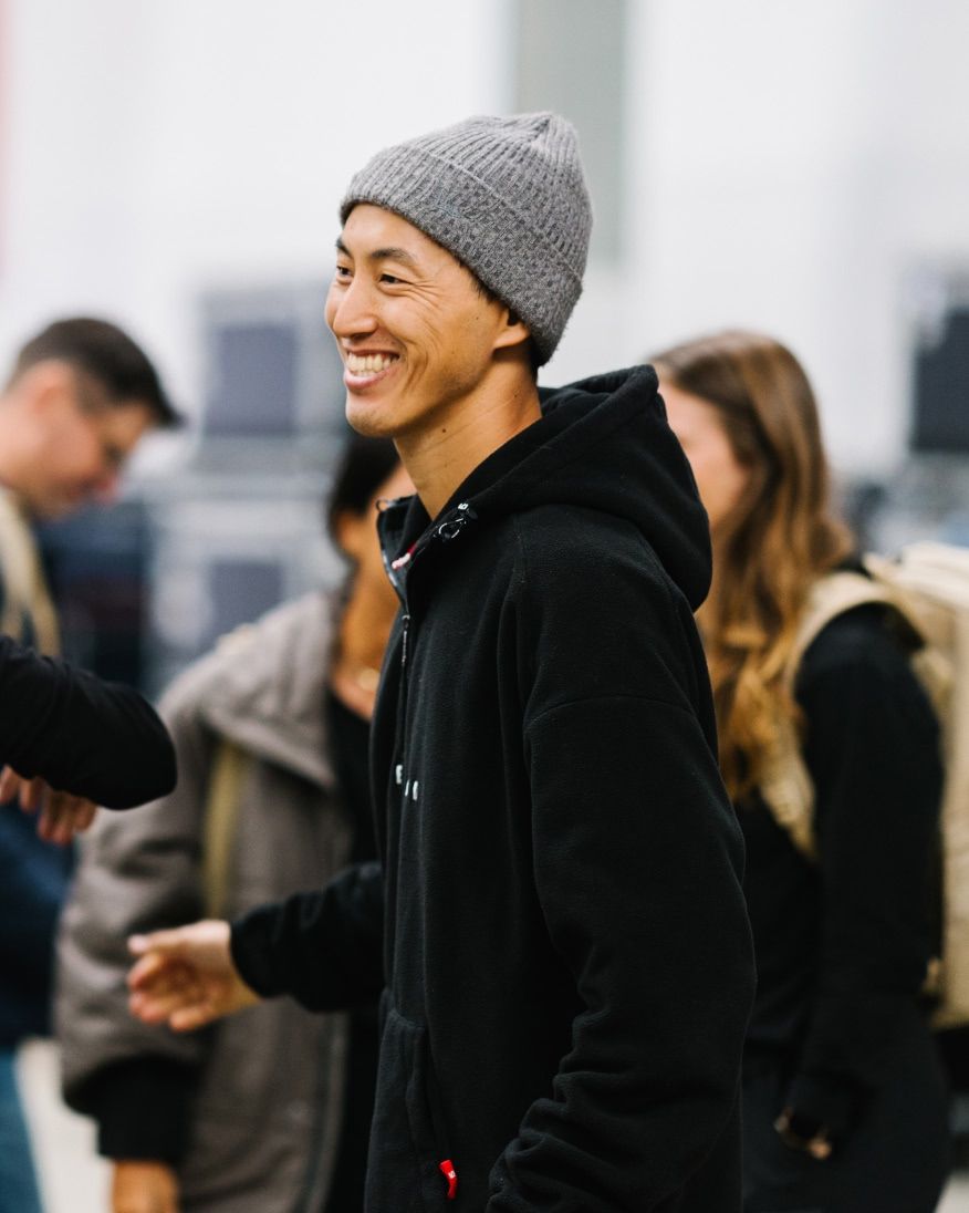 A person smiling while greeting others at an event.