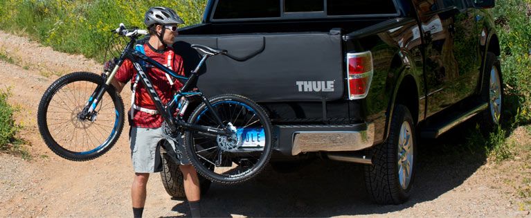 A cyclists loads his bike onto a Thule truck bed bike rack.