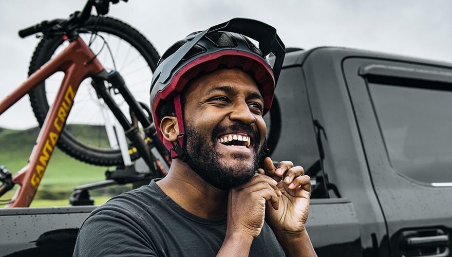 Eliot Jackson zet zijn helm vast met een pick-uptruck en een Thule fietsendrager voor trucks met een fiets achterop.
