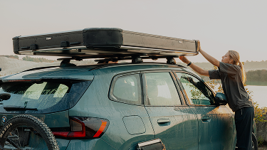 Person loading gear onto a car with Thule roof racks