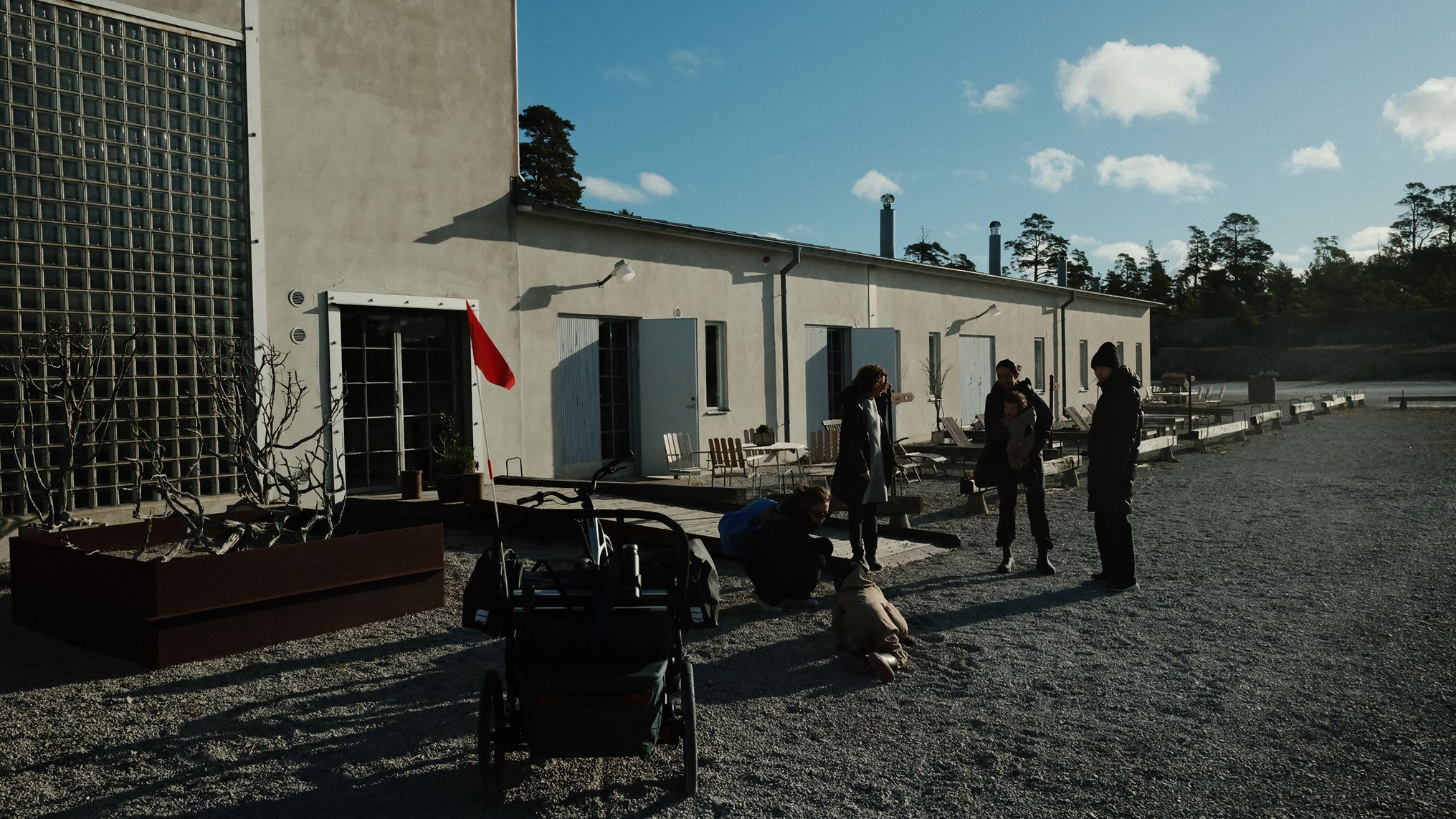 Nos bastidores da campanha A Different Kind of Strong, de Thule, com membros da equipe e Thule Chariot do lado de fora de um prédio em uma paisagem de cascalho.