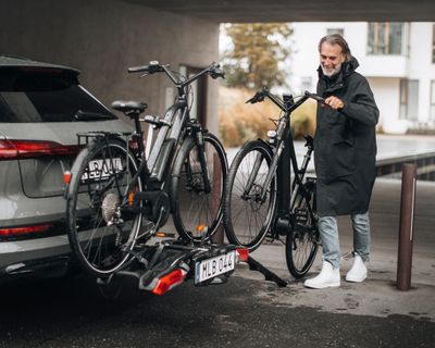 Um ciclista carrega as bicicletas num suporte de bicicleta utilizando um acessório para o mesmo.