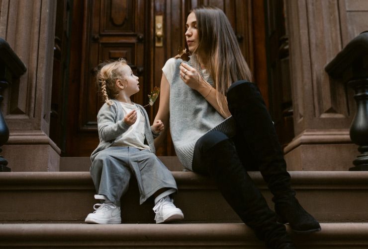 Olesia Anisimovich and her daughter sit on a stoop in New York City.