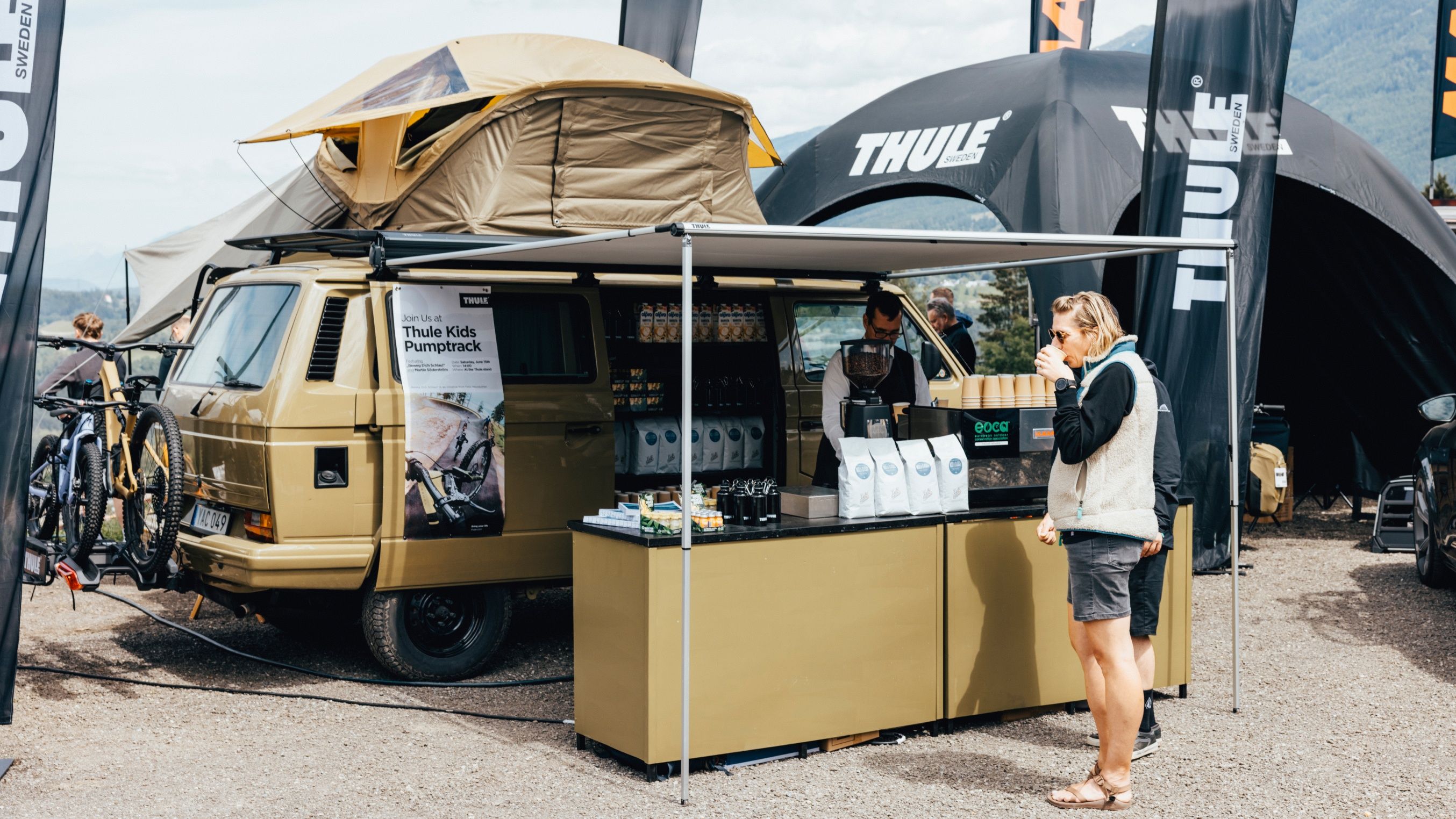 Una persona in piedi davanti allo stand del caffè del camper Thule presso il festival Crankworx Innsbruck.