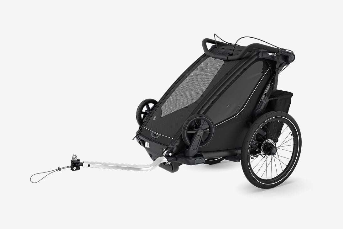 Une remorque Thule Chariot Sport 2 noire est posée sur un fond gris clair. 