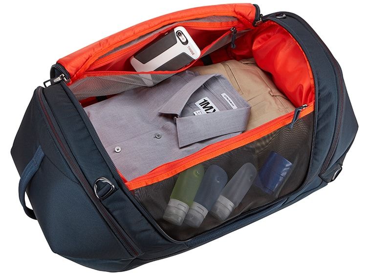 A close-up of one of the Thule duffel bags open with shits and a phone inside the inside pockets.