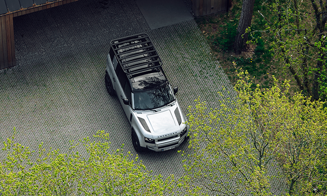 A bird's-eye view of a vehicle parked outside a garage with a Thule Caprock roof rack platform.