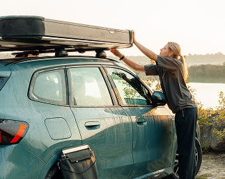 Person loading gear onto a car with Thule roof racks
