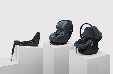 Three Thule child car seats displayed together, including an ISOFIX base, a rear-facing toddler seat, and an infant car seat in dark grey.