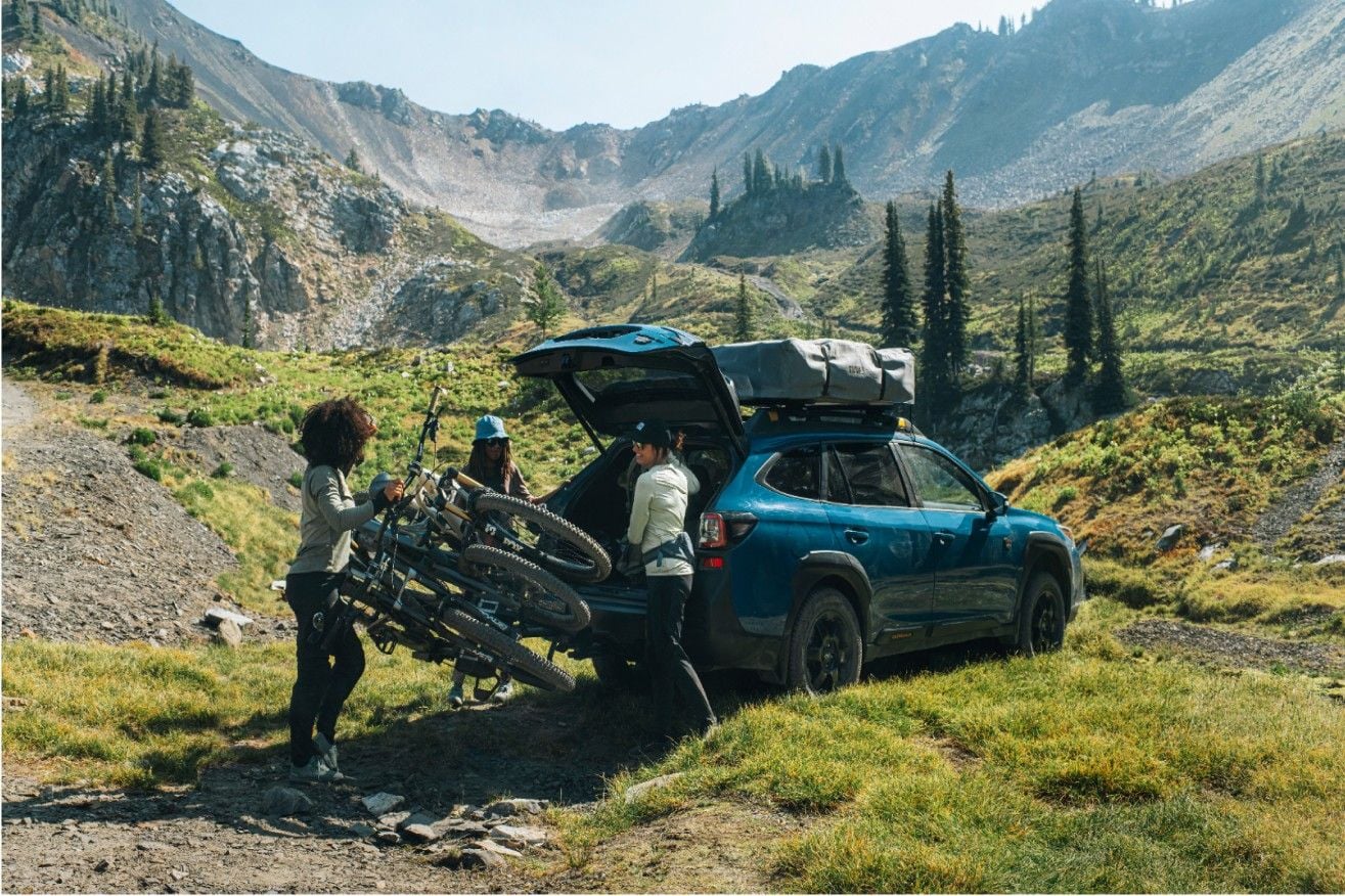 一名男子將自行車裝上圖勒屋頂的自行車架，背景是山脈和湖泊。