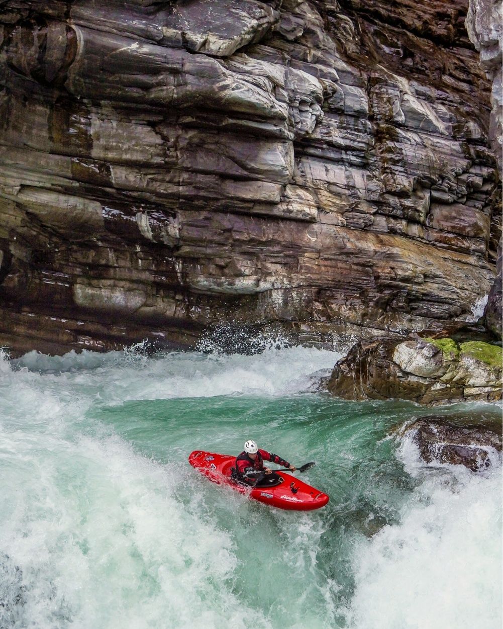 Pedro Oliva paddles in white water through a canyon.