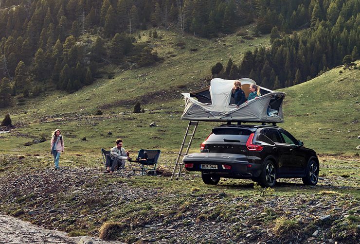 A vehicle is parked in a field with a towbar cargo box and a rooftop tent.