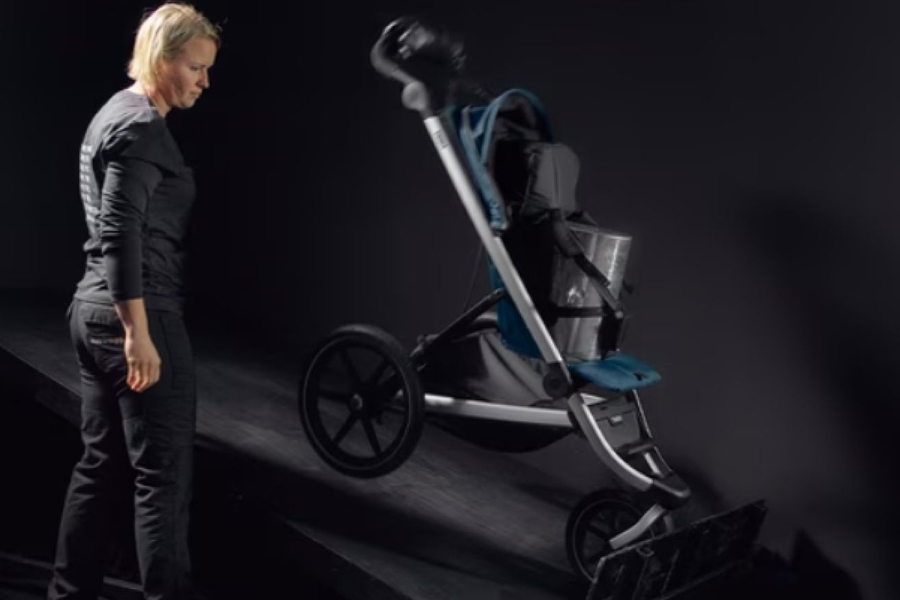A woman at the Thule test center observes the stroller being tested using the impact tests.