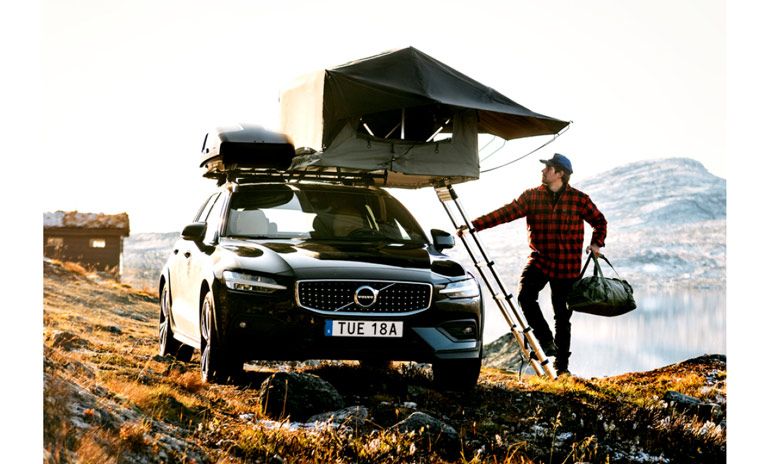 Man by a lake climbs the ladder of the Thule Tepui Foothill roof top tent.