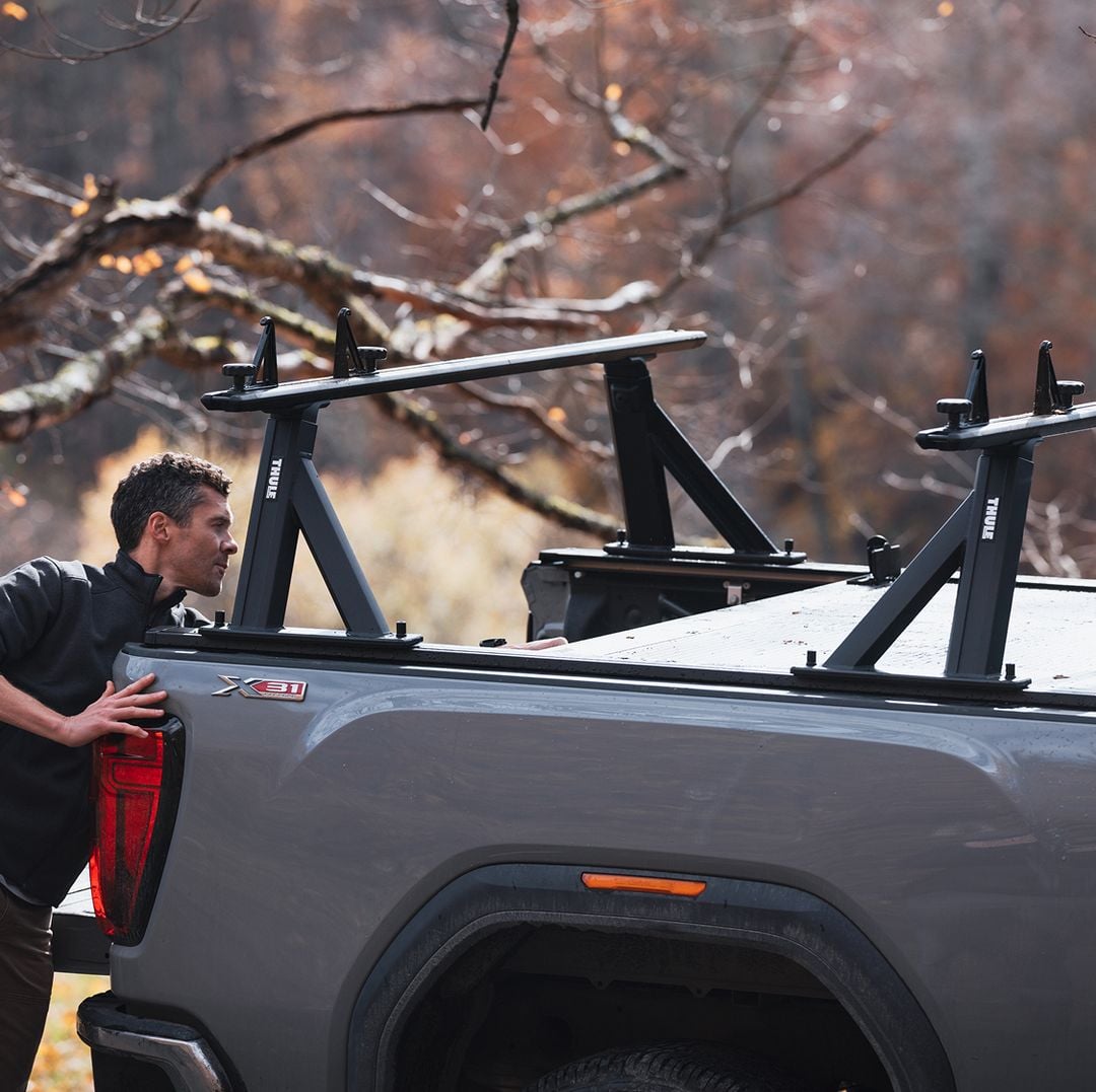 Person loading gear onto a pickup truck with a Thule Xscape truck rack.