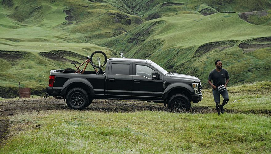 Eliot Jackson kõnnib pikap-auto kõrval, millel on Thule BedRider jalgrattahoidik ja jalgrattad.