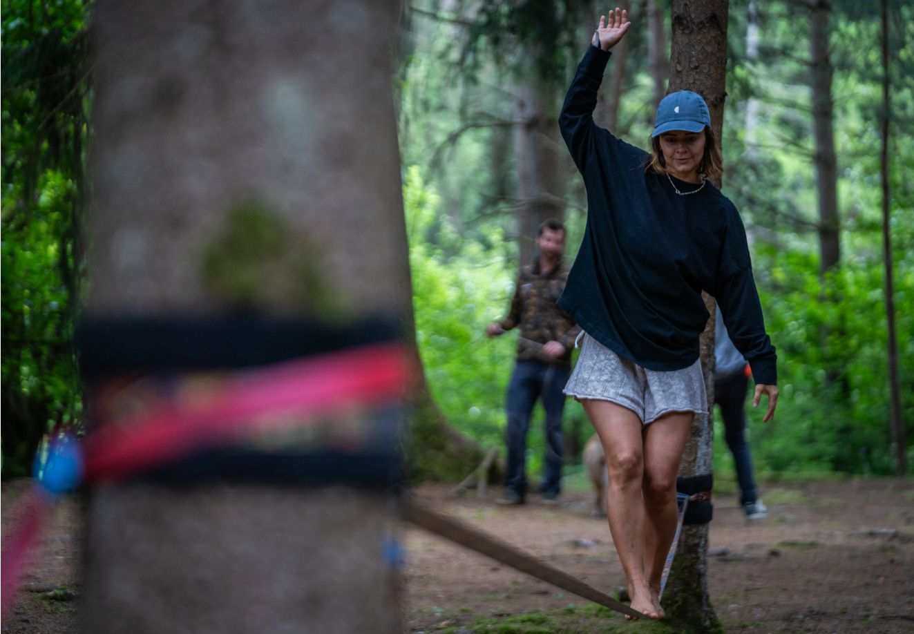 Человек идет по канату, натянутому между двумя деревьями, на мероприятии Adventure Life by Thule.