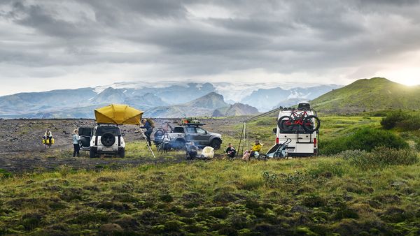 A van and jeep is parked among the mountains with a rooftop tent, bike racks, bike trailers and more.