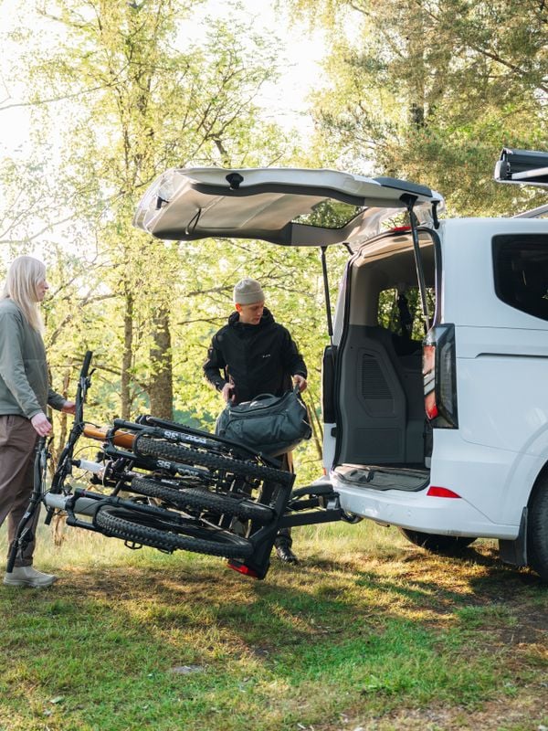 A car, people and Thule bike rack in green landscape