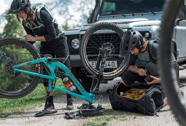 Two cyclists fix a mountain bike with the help of gear inside their Thule bike duffel bag